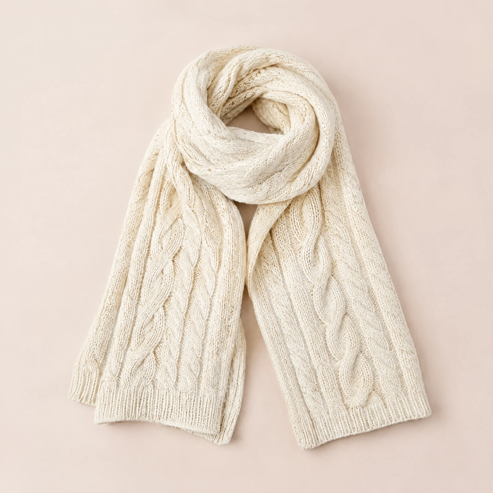 Ivory chunky cable scarf wrapped and draped on a blush background