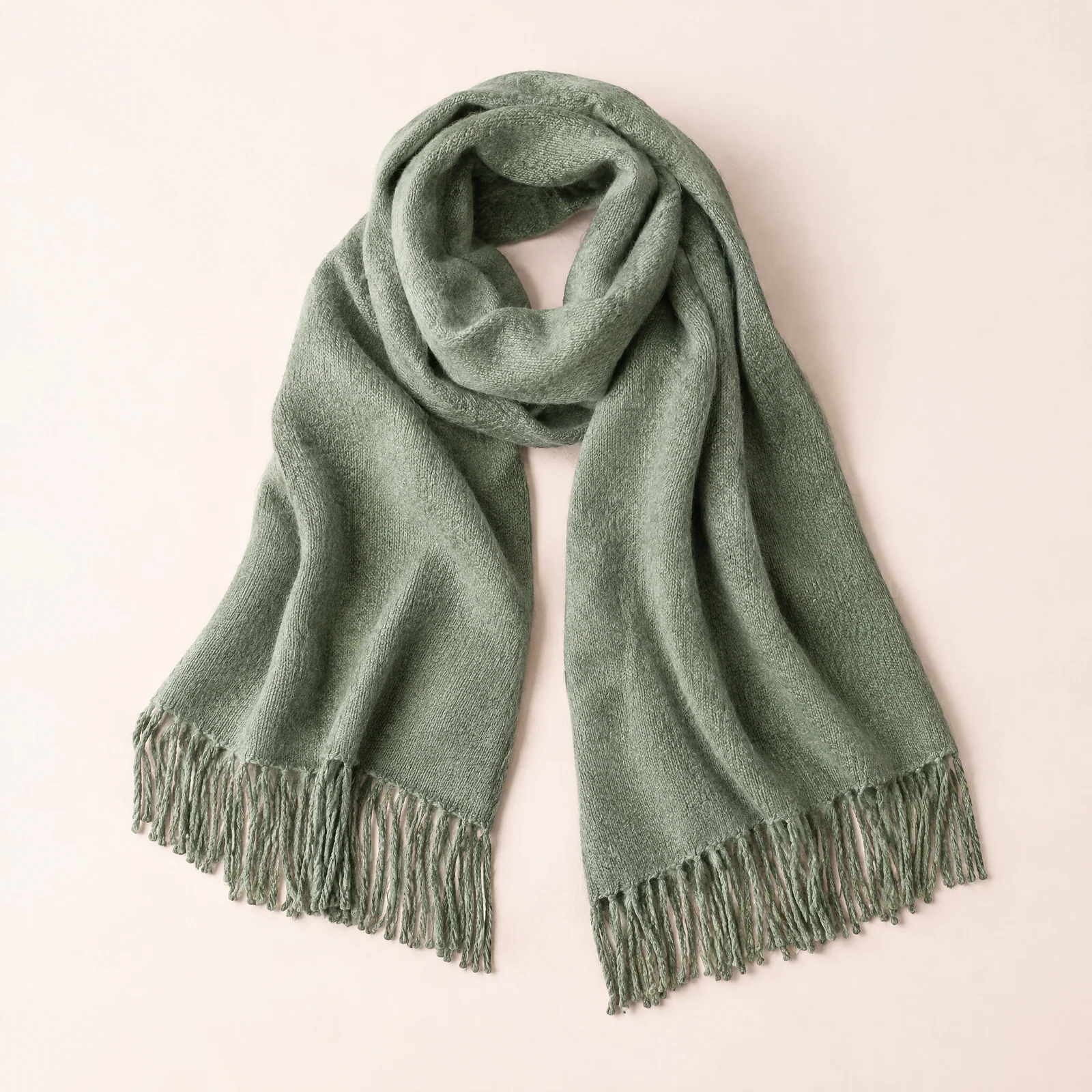 Sage green fringed wrap shawl softly draped on a blush background